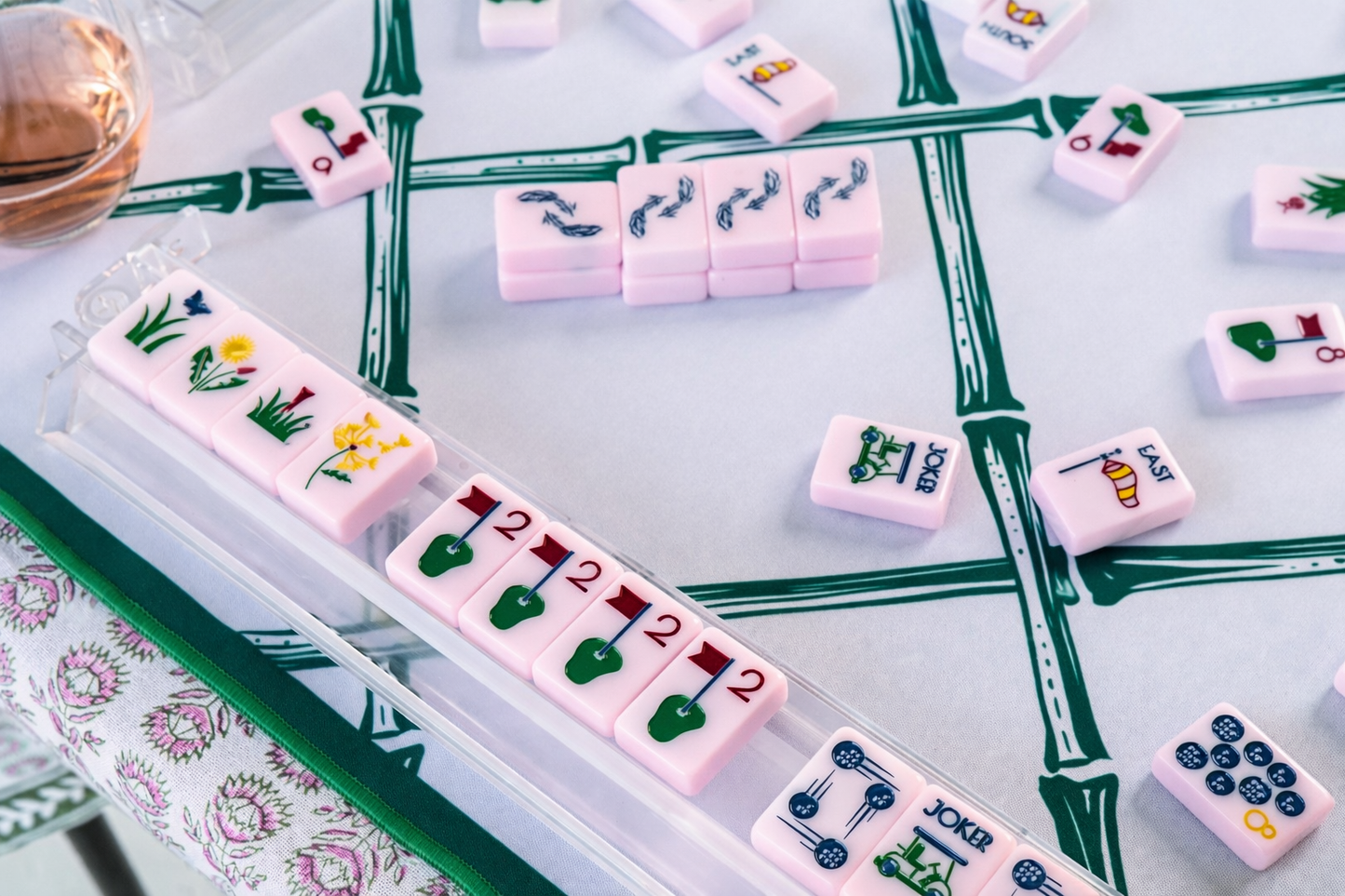 Pink mahjong tiles on a green and white trellis playing mat 