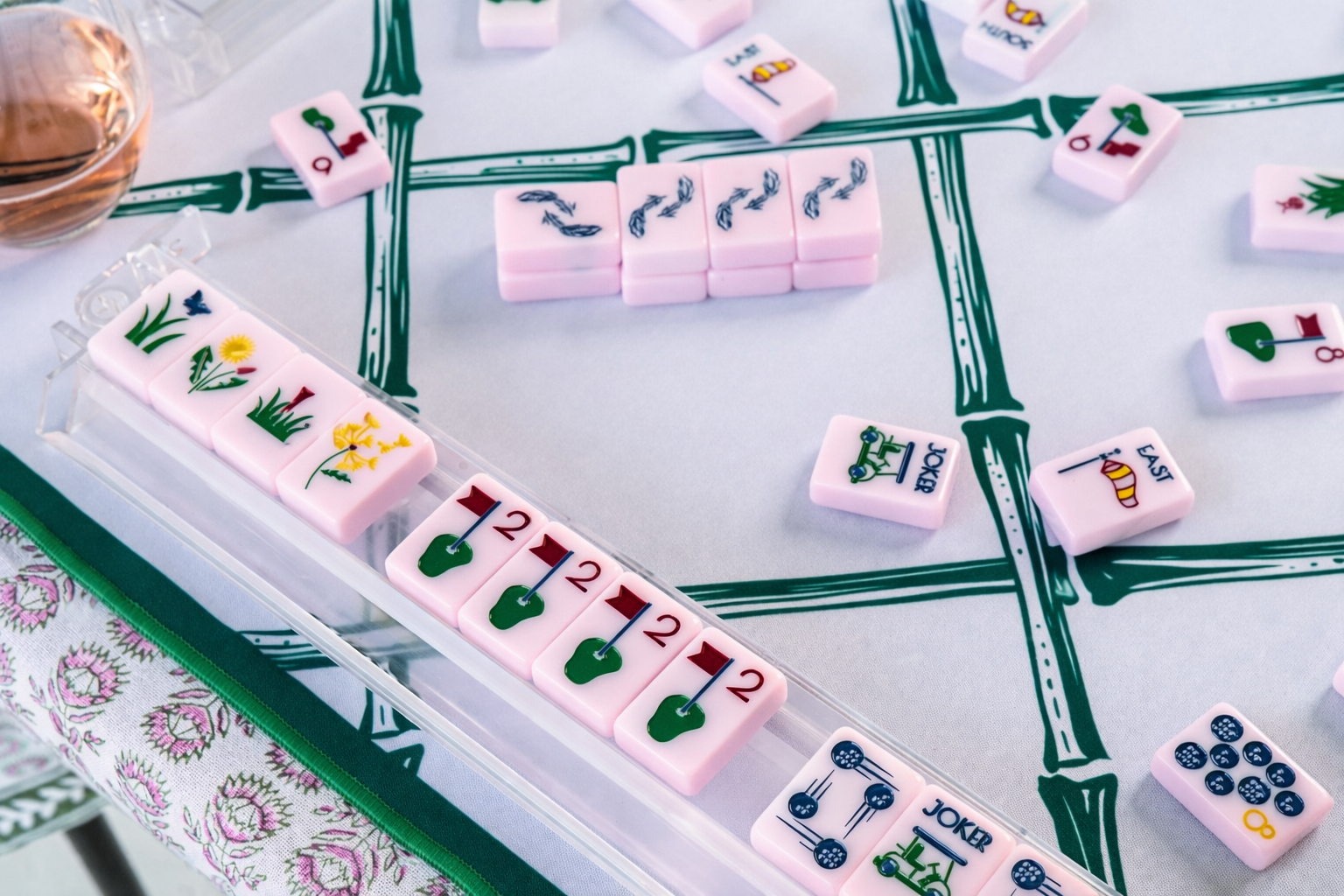 Pink mahjong tiles on a green and white trellis playing mat 
